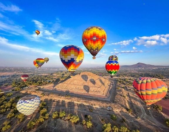 Vista panorámica de Teotihuacán con globos y pirámides al fondo